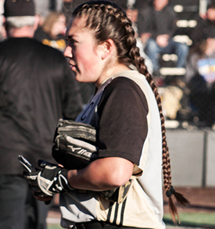softball player in pigtails standing