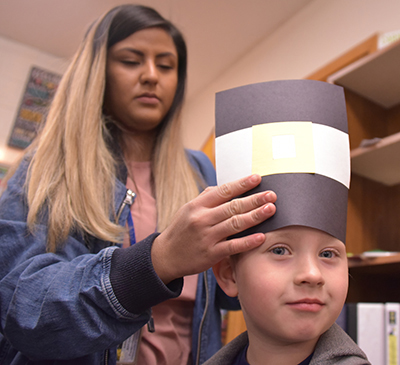 teacher putting pilgrim hat on student