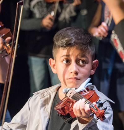 kid playing violin looking at teacher