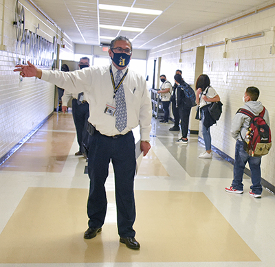 principal standing in hall pointing directions
