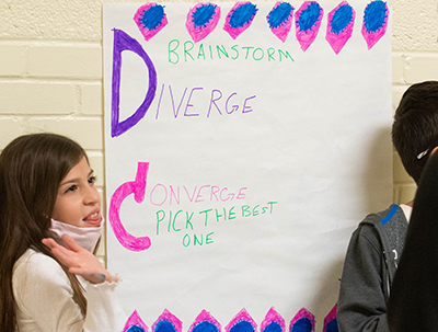 girl standing in front of poster she drew